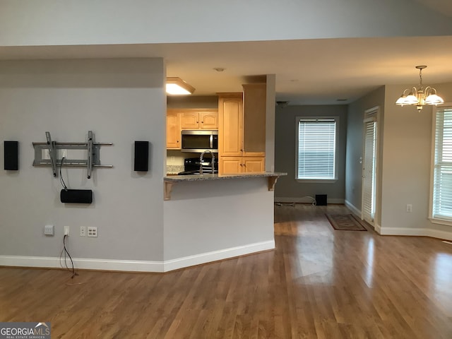 kitchen featuring black range oven, stone countertops, wood-type flooring, and a chandelier