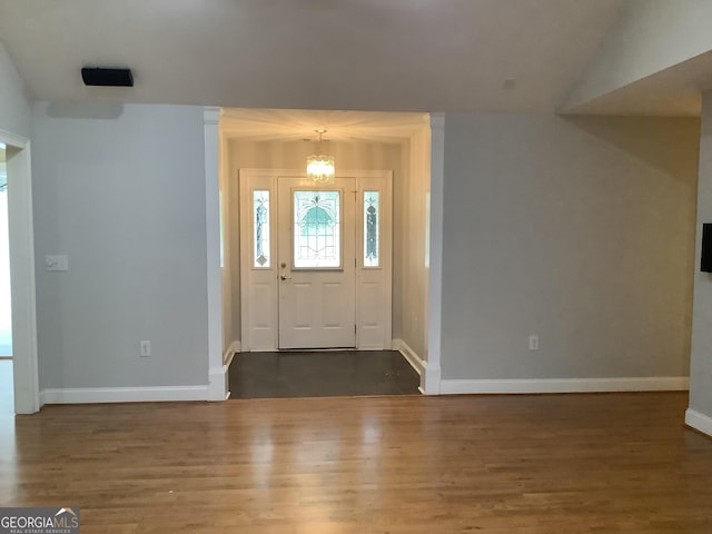 foyer with dark wood-type flooring, lofted ceiling, and an inviting chandelier