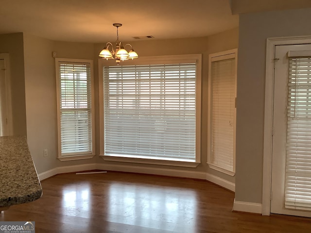 unfurnished dining area with hardwood / wood-style flooring and an inviting chandelier