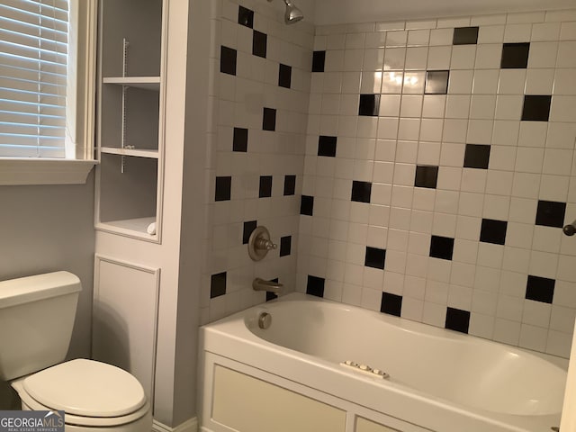 bathroom featuring tiled shower / bath combo and toilet