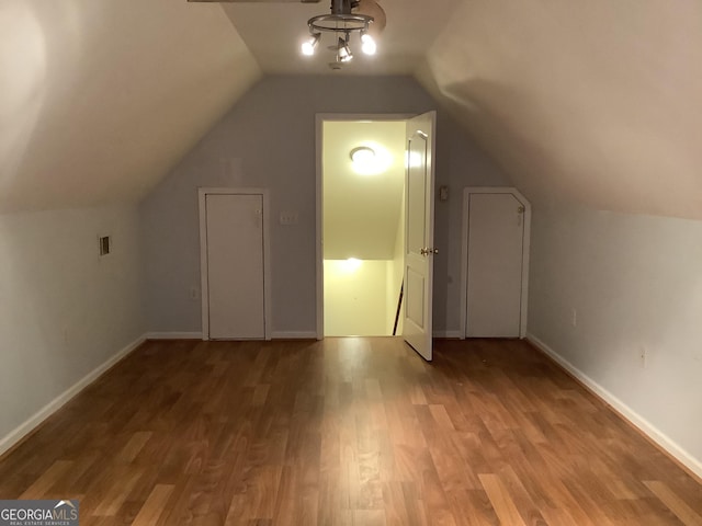 additional living space with hardwood / wood-style floors and vaulted ceiling