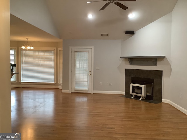 unfurnished living room with hardwood / wood-style floors, ceiling fan with notable chandelier, and lofted ceiling