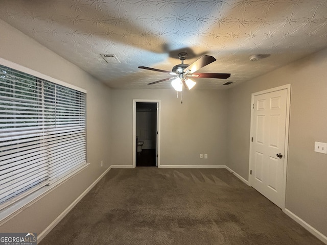 unfurnished room featuring a textured ceiling, ceiling fan, and dark colored carpet