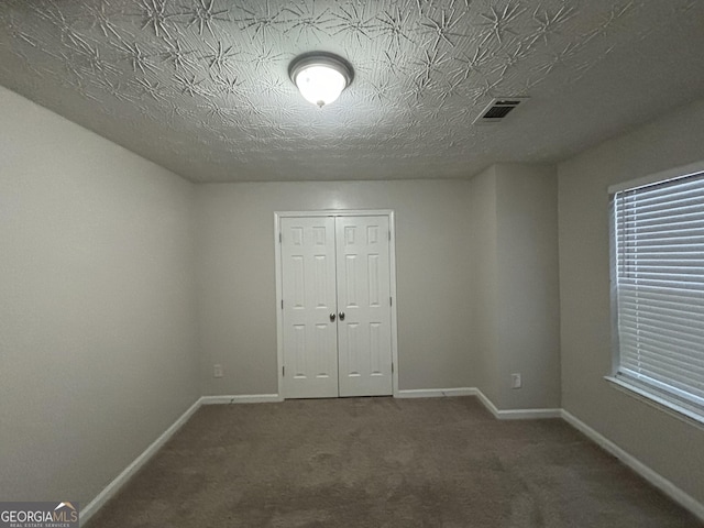 unfurnished bedroom featuring dark carpet and a closet