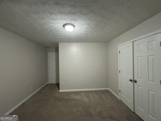 unfurnished bedroom featuring a closet, a textured ceiling, and dark colored carpet