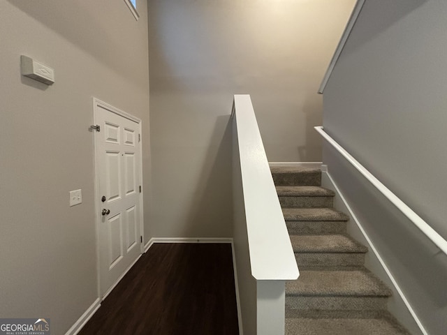 stairway with a towering ceiling and hardwood / wood-style flooring