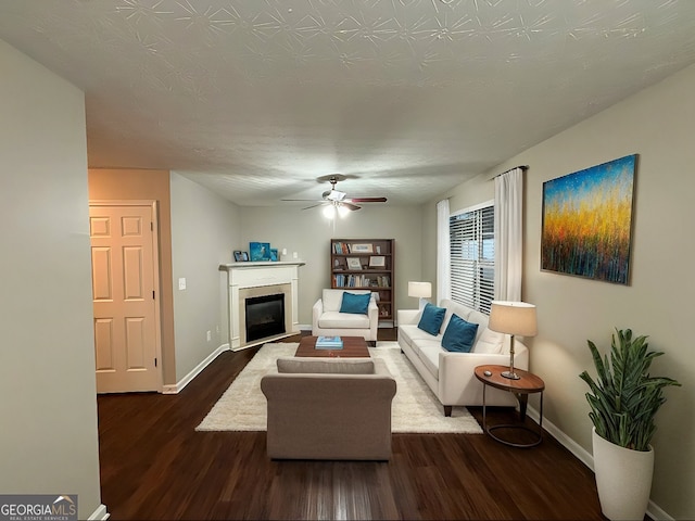 living room featuring ceiling fan, dark wood-type flooring, and a textured ceiling