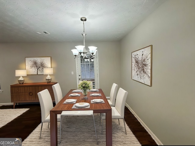 dining room with dark hardwood / wood-style flooring and an inviting chandelier