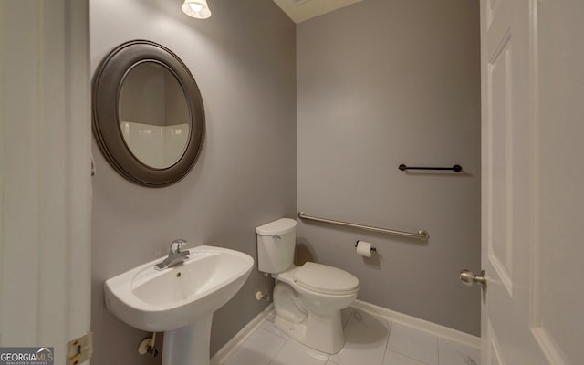 bathroom with toilet, sink, and tile patterned flooring