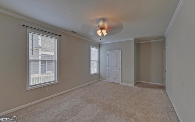 carpeted empty room featuring a textured ceiling, ceiling fan, and crown molding