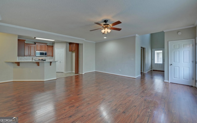 unfurnished living room featuring dark wood-type flooring, ceiling fan, and crown molding