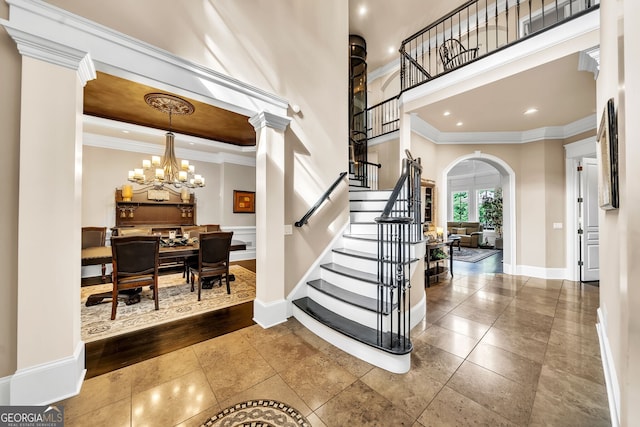 foyer with a high ceiling, wood-type flooring, crown molding, and a notable chandelier