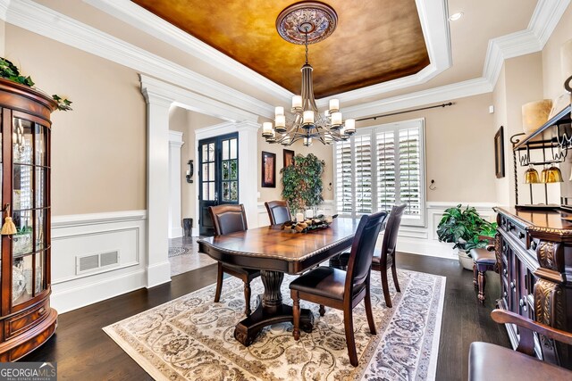 dining area featuring ornate columns, ornamental molding, dark hardwood / wood-style floors, and a raised ceiling