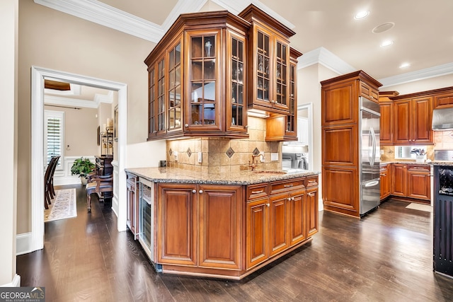 kitchen with sink, ornamental molding, light stone countertops, stainless steel built in refrigerator, and dark hardwood / wood-style flooring