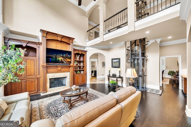 living room with dark wood-type flooring, crown molding, and a towering ceiling