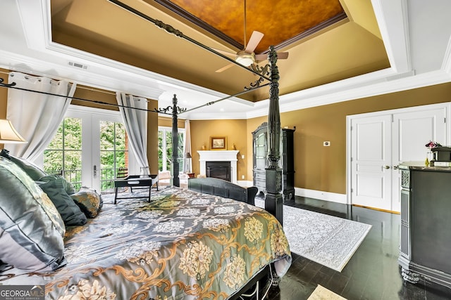 bedroom featuring dark hardwood / wood-style flooring, access to exterior, crown molding, and a tray ceiling