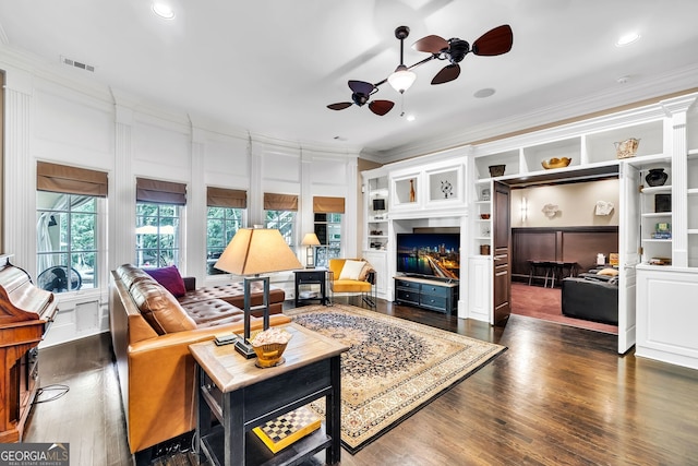 living room featuring built in shelves, ceiling fan, crown molding, and dark hardwood / wood-style flooring