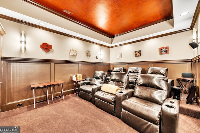 carpeted home theater room featuring crown molding and a tray ceiling