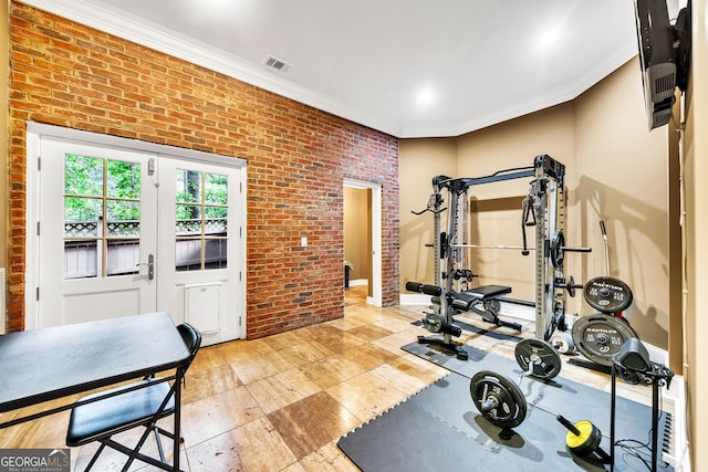 exercise room featuring ornamental molding and brick wall