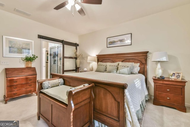 carpeted bedroom featuring a barn door and ceiling fan