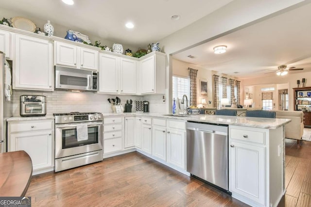 kitchen featuring kitchen peninsula, white cabinets, dark wood-type flooring, and appliances with stainless steel finishes