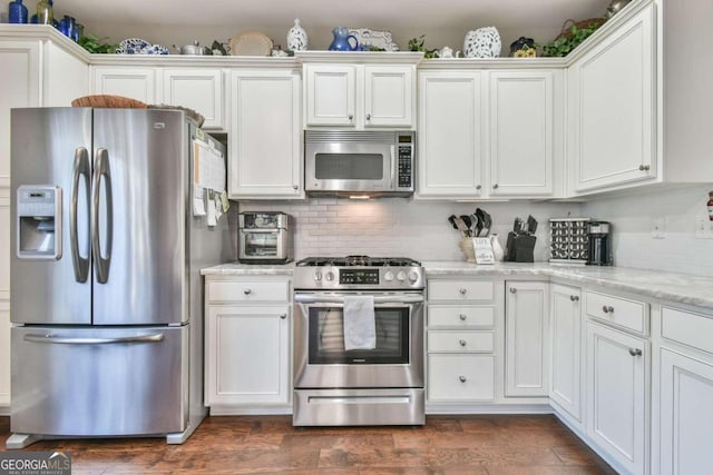 kitchen with white cabinetry, appliances with stainless steel finishes, light stone countertops, and dark wood-type flooring