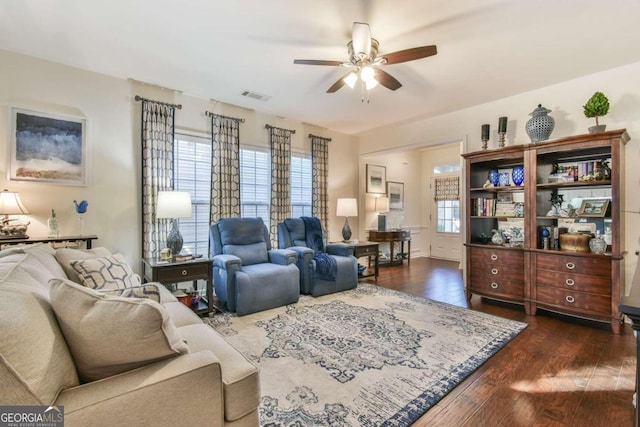 living room featuring dark wood-type flooring, ceiling fan, and a healthy amount of sunlight