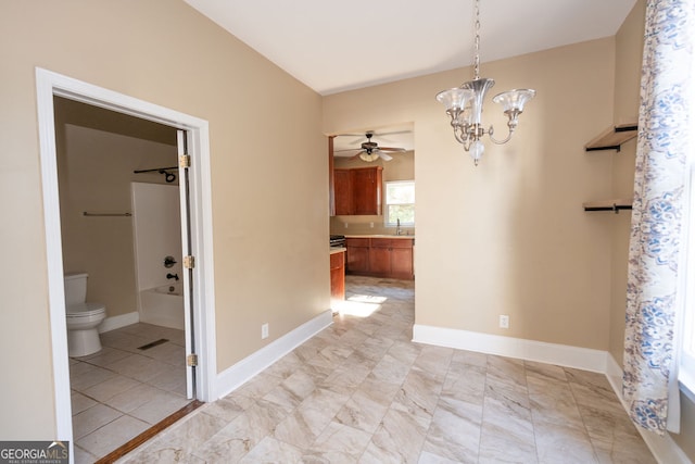 unfurnished dining area featuring ceiling fan with notable chandelier and sink