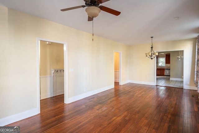 spare room with dark wood-type flooring and ceiling fan with notable chandelier