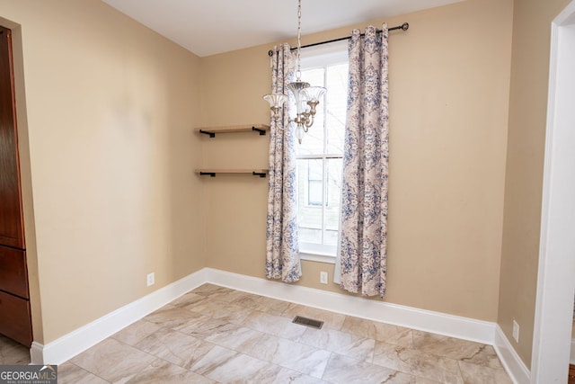 spare room with a wealth of natural light and an inviting chandelier