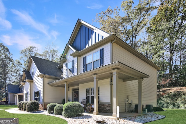 view of front of house with covered porch, central air condition unit, and a front yard