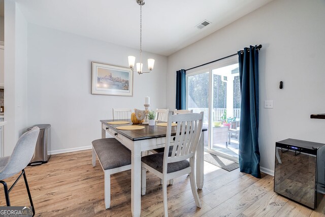 dining room with light hardwood / wood-style floors and an inviting chandelier