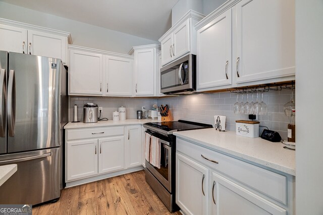 kitchen featuring light hardwood / wood-style flooring, backsplash, appliances with stainless steel finishes, and white cabinets