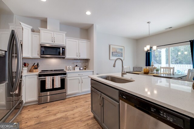 kitchen with stainless steel appliances, white cabinetry, sink, and light wood-type flooring