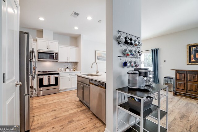 kitchen featuring white cabinets, stainless steel appliances, sink, and light hardwood / wood-style flooring