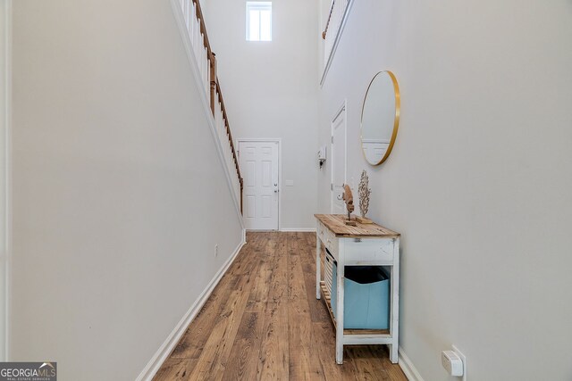 hallway featuring light wood-type flooring and a towering ceiling