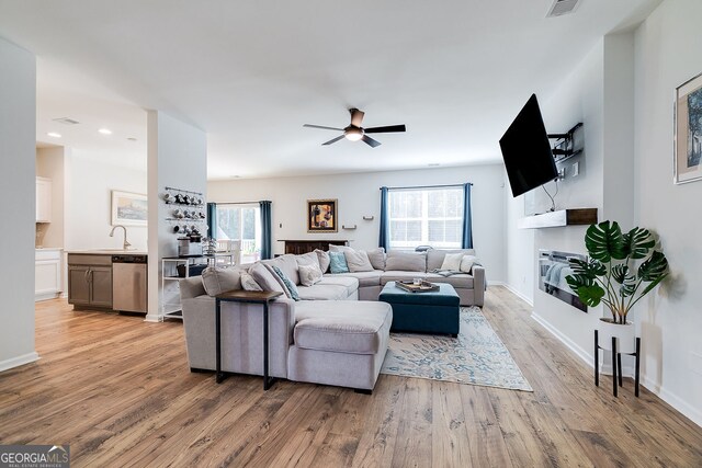 living room featuring sink, ceiling fan, and light hardwood / wood-style flooring