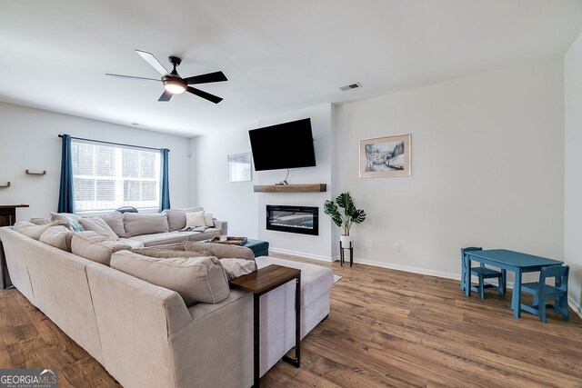 living room featuring dark wood-type flooring and ceiling fan