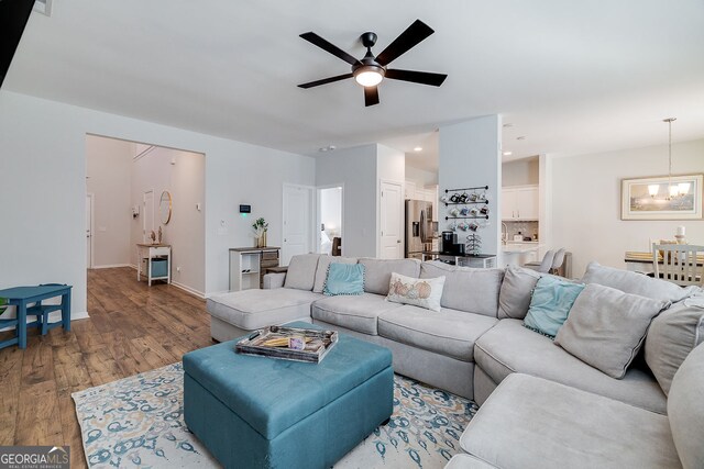 living room with ceiling fan with notable chandelier and hardwood / wood-style flooring