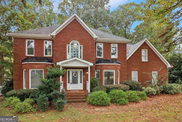 colonial-style house featuring a standing seam roof, brick siding, and metal roof