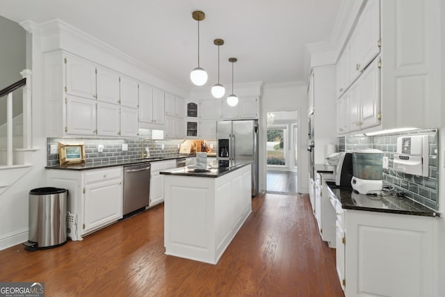 kitchen with crown molding, stainless steel appliances, white cabinets, dark wood-type flooring, and a center island