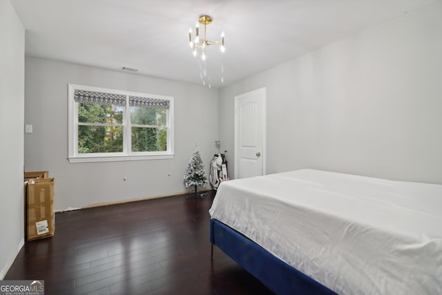 bedroom with dark hardwood / wood-style flooring and an inviting chandelier