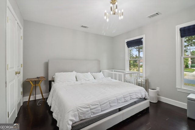 bedroom with dark wood-type flooring and a chandelier