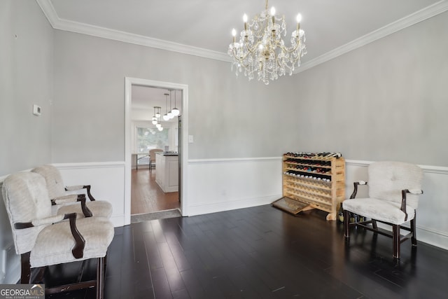 living area with a wainscoted wall, crown molding, dark wood-type flooring, and an inviting chandelier