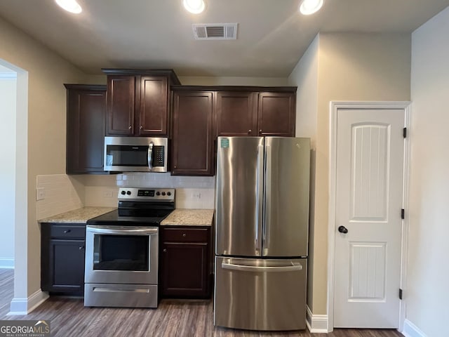 kitchen featuring stainless steel appliances, dark brown cabinetry, light stone countertops, and dark hardwood / wood-style floors