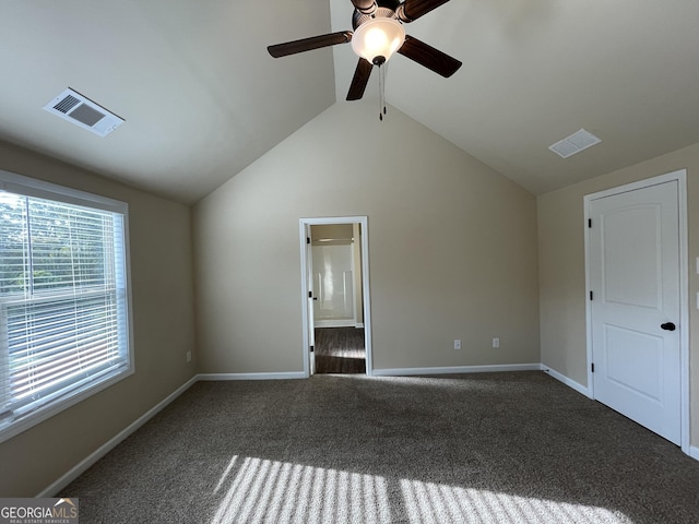 unfurnished bedroom with ceiling fan, dark carpet, connected bathroom, and vaulted ceiling