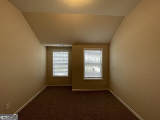 carpeted spare room with lofted ceiling