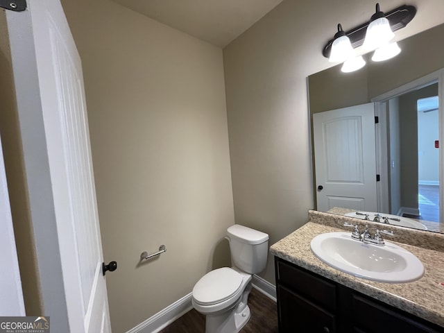 bathroom with toilet, vanity, and hardwood / wood-style flooring