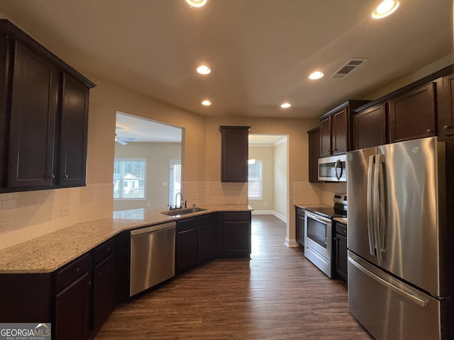 kitchen featuring light stone counters, stainless steel appliances, tasteful backsplash, dark hardwood / wood-style flooring, and sink