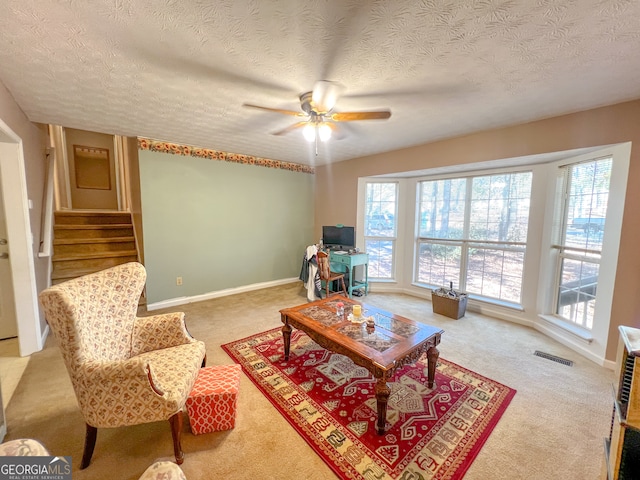 carpeted living room with ceiling fan and a textured ceiling